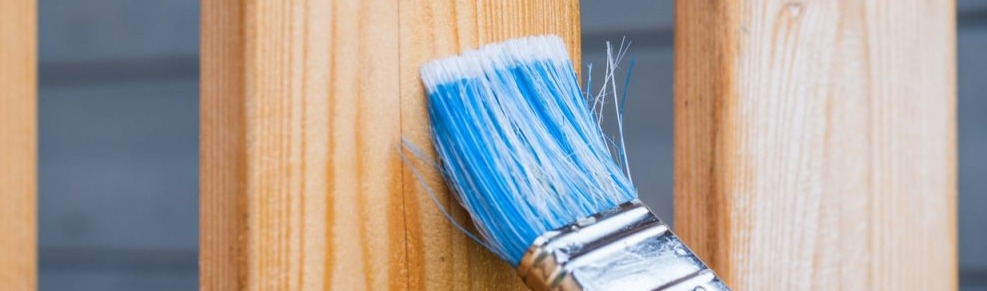 paint brush going against a wooden railing