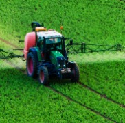 Tractor in field spraying fertilizer, a variable input or expense.