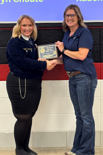 A BTC Bank employee presenting an award to an FFA member on stage