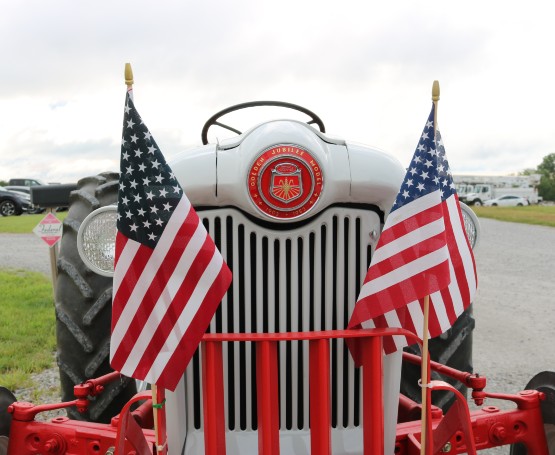 an old tractor with two American flags on the front
