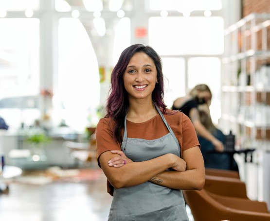 a small business owner poses for a photo while customers shop behind her