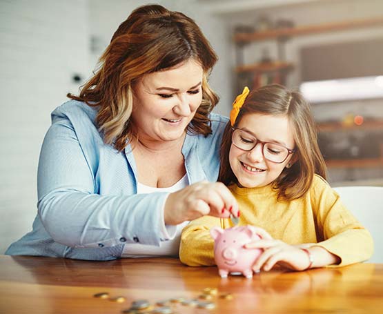 Mom and child putting coins in a piggy bank.