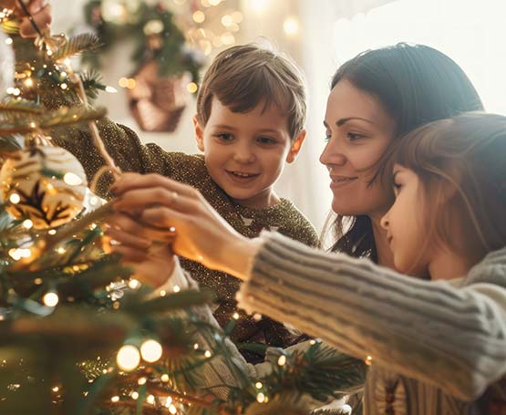 Mom and two kids decorating a Christmas tree.