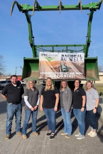 A group of BTC Bank employees smiling in front of a tractor for National Ag Week