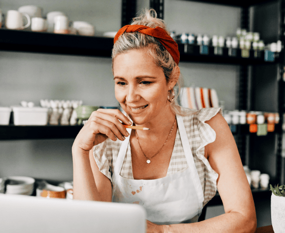 A small business owner looking at her computer in her pottery shop