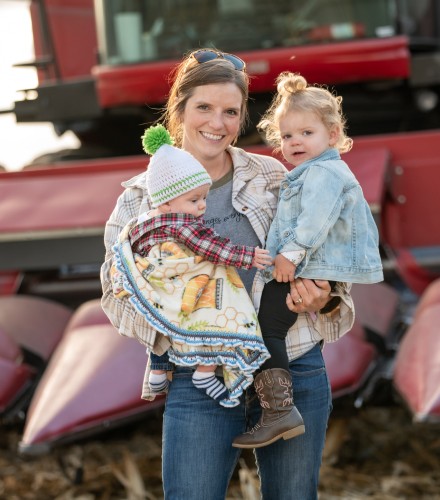 a mother holds her children posing for a photo infront of their combine