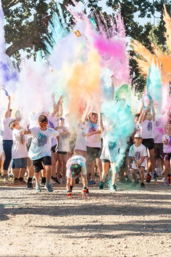 A group of children excitedly beginning to run in clouds of colorful dust