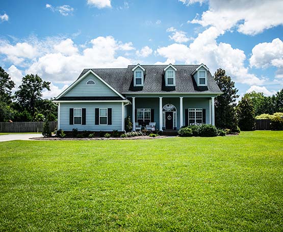 The front of a home with green grass and a blue sky.