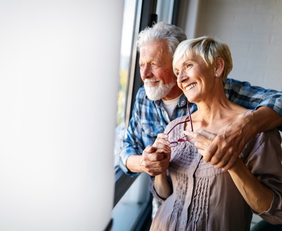 an older couple embracing while looking out the window