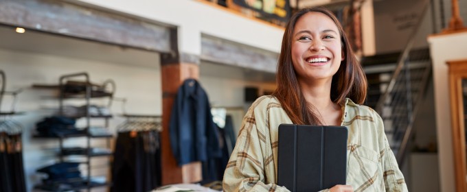 Woman standing with her ipad while in her clothing shop