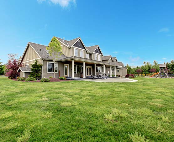 A large home with yard and blue skies.