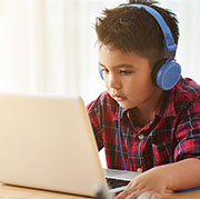 Boy with headphones using laptop.