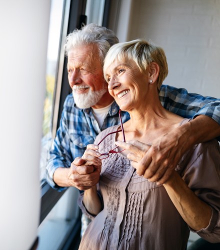 an older couple embraces while looking out the window