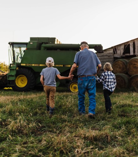 a grandfather and his grand kids walk together towards a combine