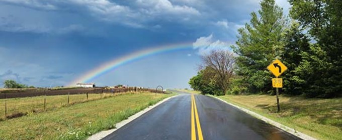 a road stretching into the distance with a rainbow overhead