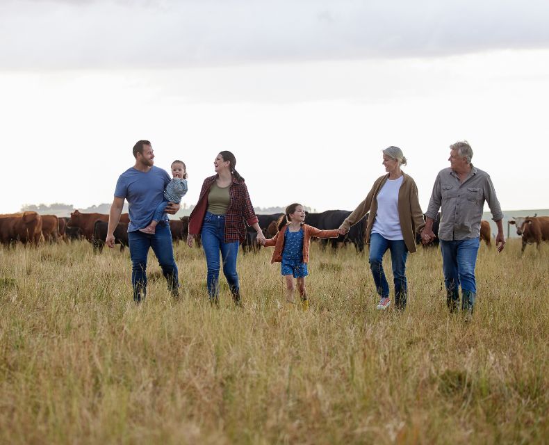 a generational family walks through a cow pasture 