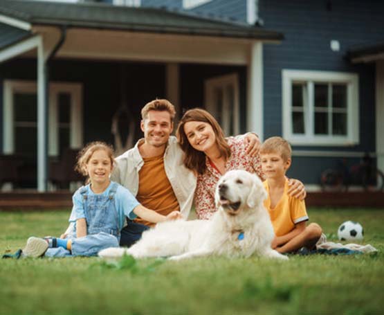 Parents, two kids and dog in the front yard of their home.