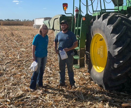 a BTC employee stands in a field with a customer next to their tractor