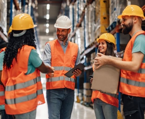 A group of employees standing in an aisle in a warehouse talking and laughin