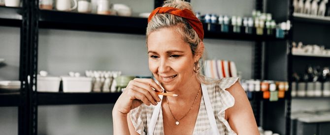 A small business owner looking at her computer in her pottery shop