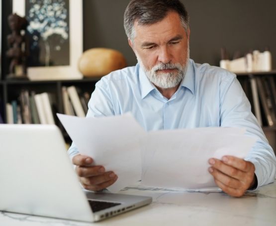A businessman reviewing papers in front of his laptop in his office
