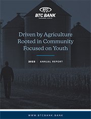 BTC Bank 2023 Annual Report Cover artwork. Farmer walking in a field background with the words "Driven by Agriculture. Rooted in Community. Focused on Youth." typed.