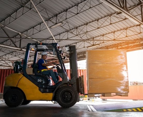 A man moving a pallet of boxes using a fork lift