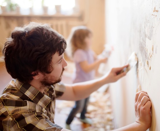 Dad and daughter working on a wall in their home