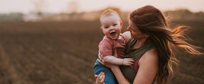 Mom and child in a farm field at dusk.