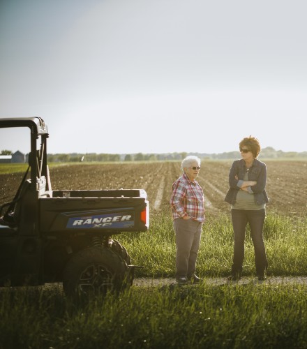 a couple of woman stand in a field