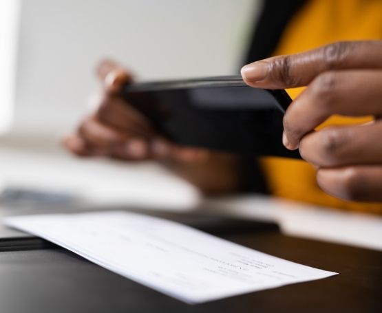 Hands holding a phone taking a photo of a check to deposit remotely