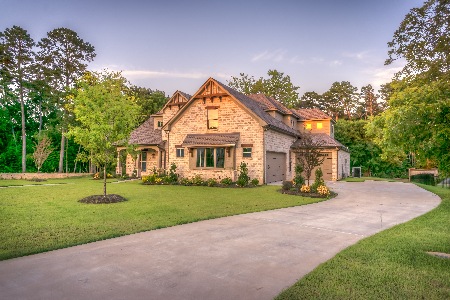 Home with long driveway surrounded by trees.