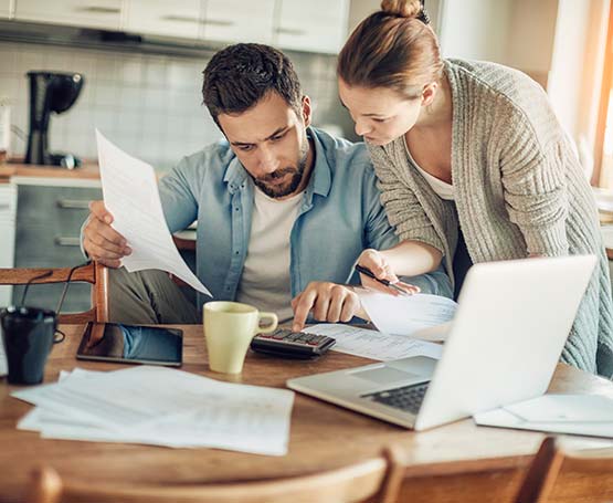 Couple looking at paperwork using a calculator.